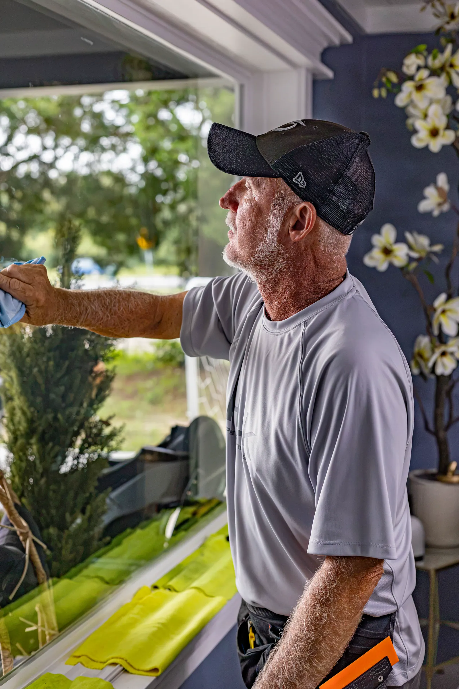 Robert, owner of Lights Out Tinting, wiping down a freshly filmed window inside a customer's home