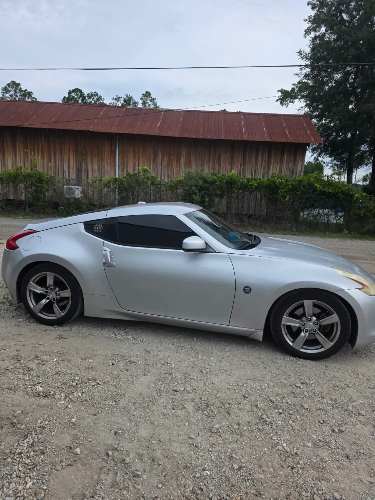 A silver Nissan 370Z sports coupe with tinted windows on the shop lot.