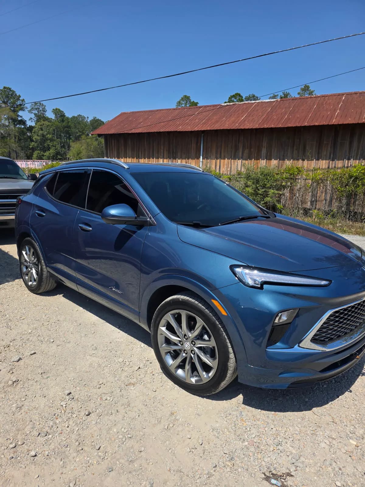 A blue Buick crossover with freshly tinted windows parked on the lot.