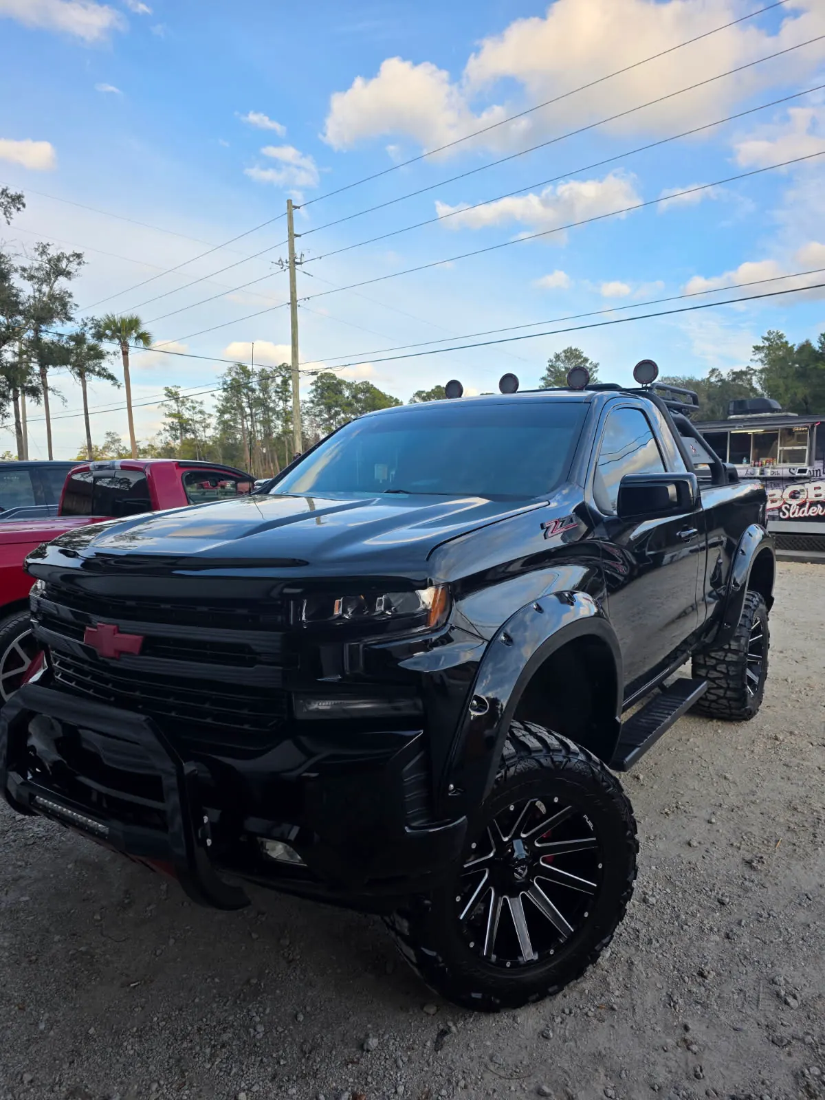 A lifted black pickup on oversized wheels with dark tinted windows.