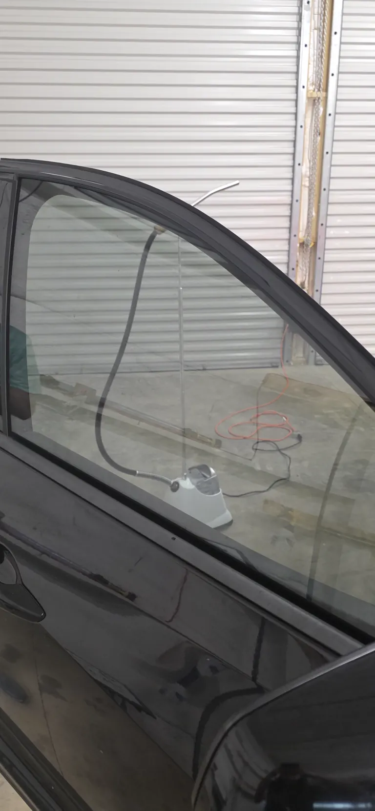 Fresh film going onto a black sedan's front window during a hand install