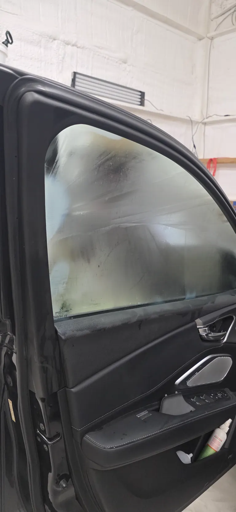 Newly applied window film curing on a black SUV's front door, water still setting under the film