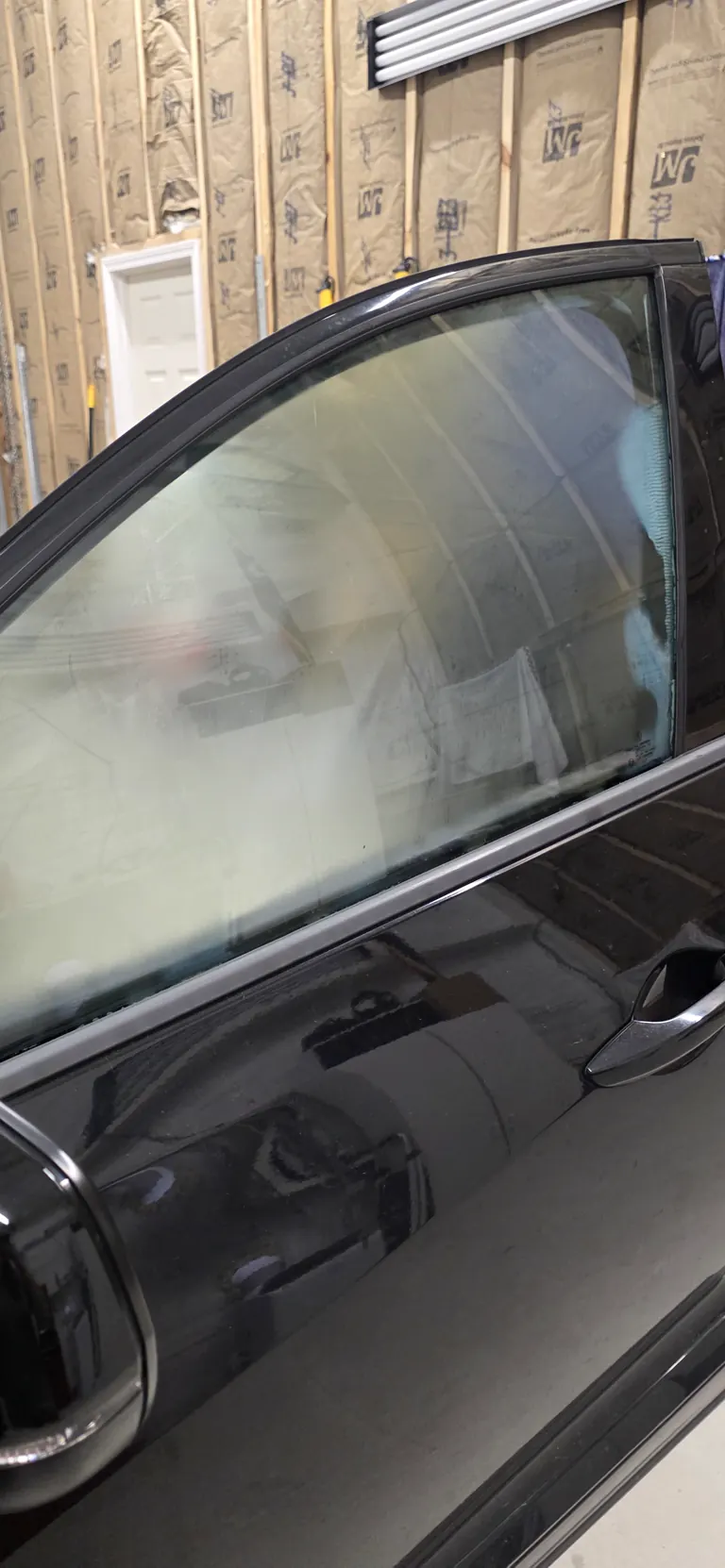 Tinted front door window on a black sedan with a clean line along the glass edge