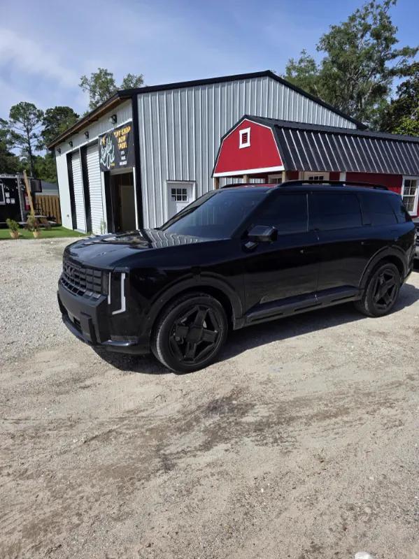 Blacked-out Kia Telluride with fresh tint outside the shop