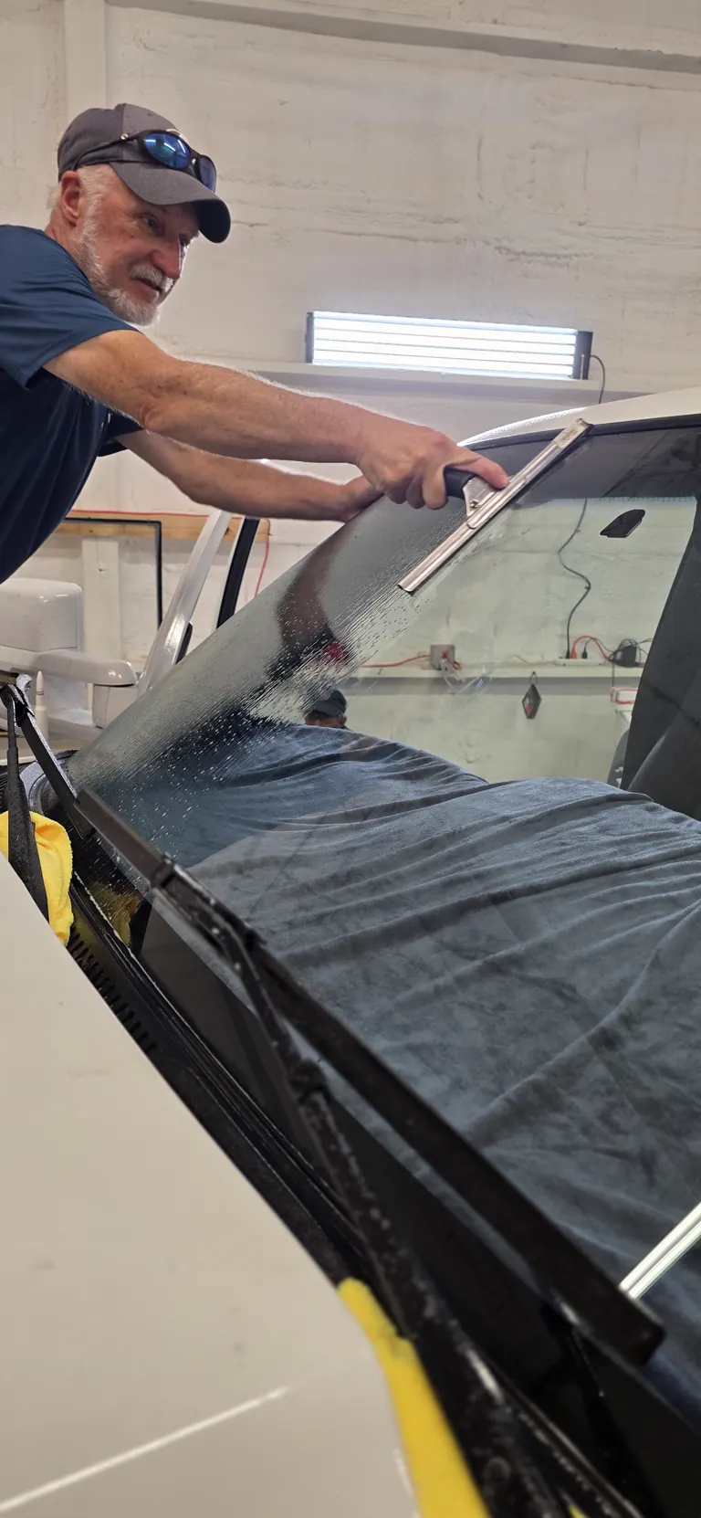 Squeegeeing fresh film onto a windshield in the Freeport shop